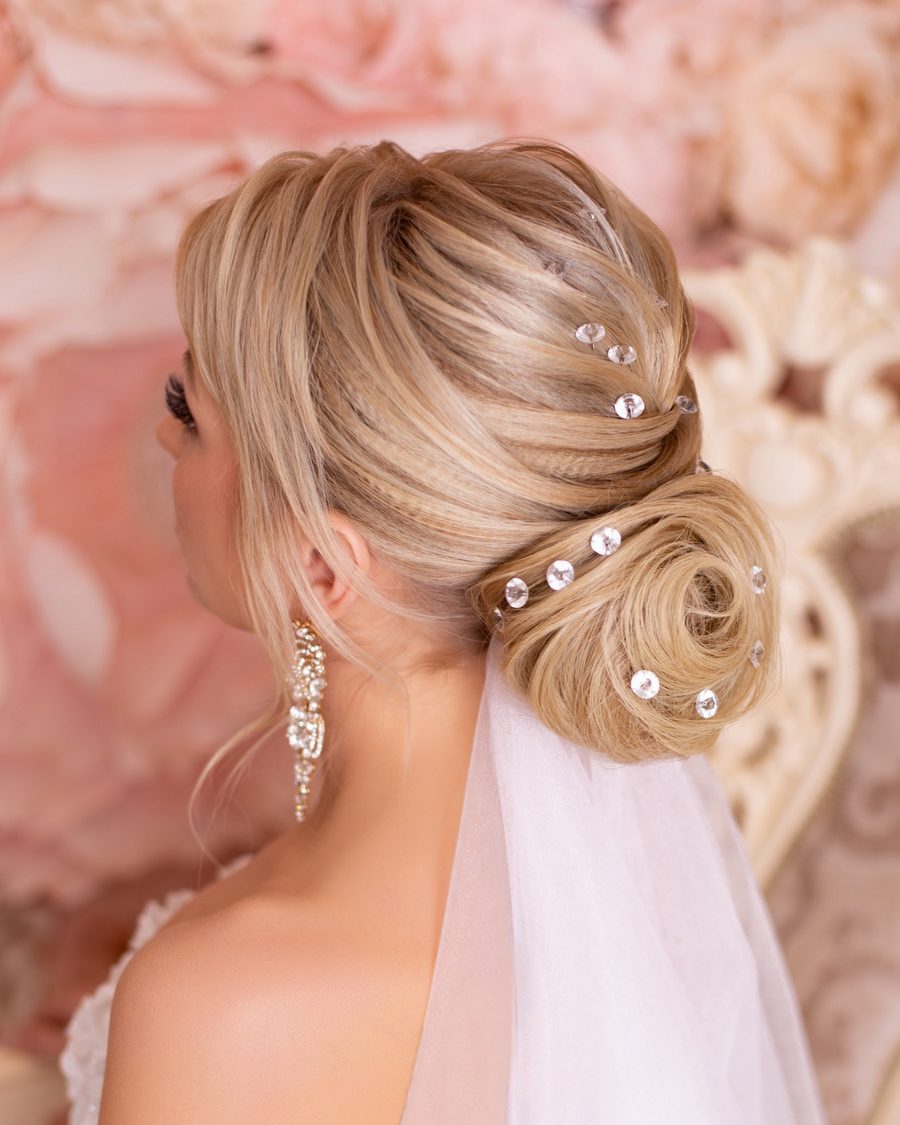 Sleek blonde chignon with crystal pins and a veil