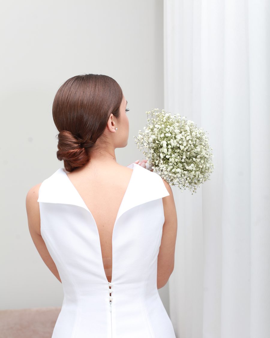Sleek low ponytail from behind, finished with gypsophila