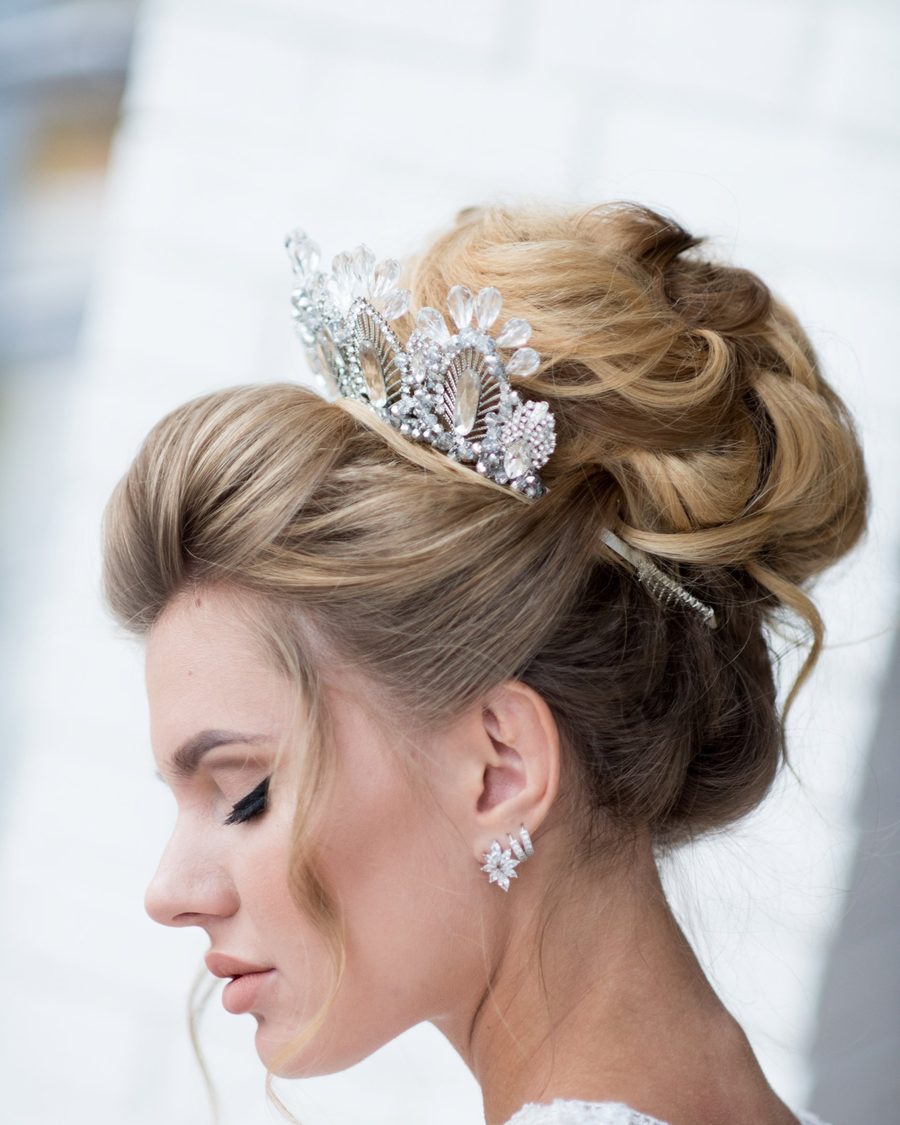 High bridal updo with a crystal tiara, soft face-framing pieces
